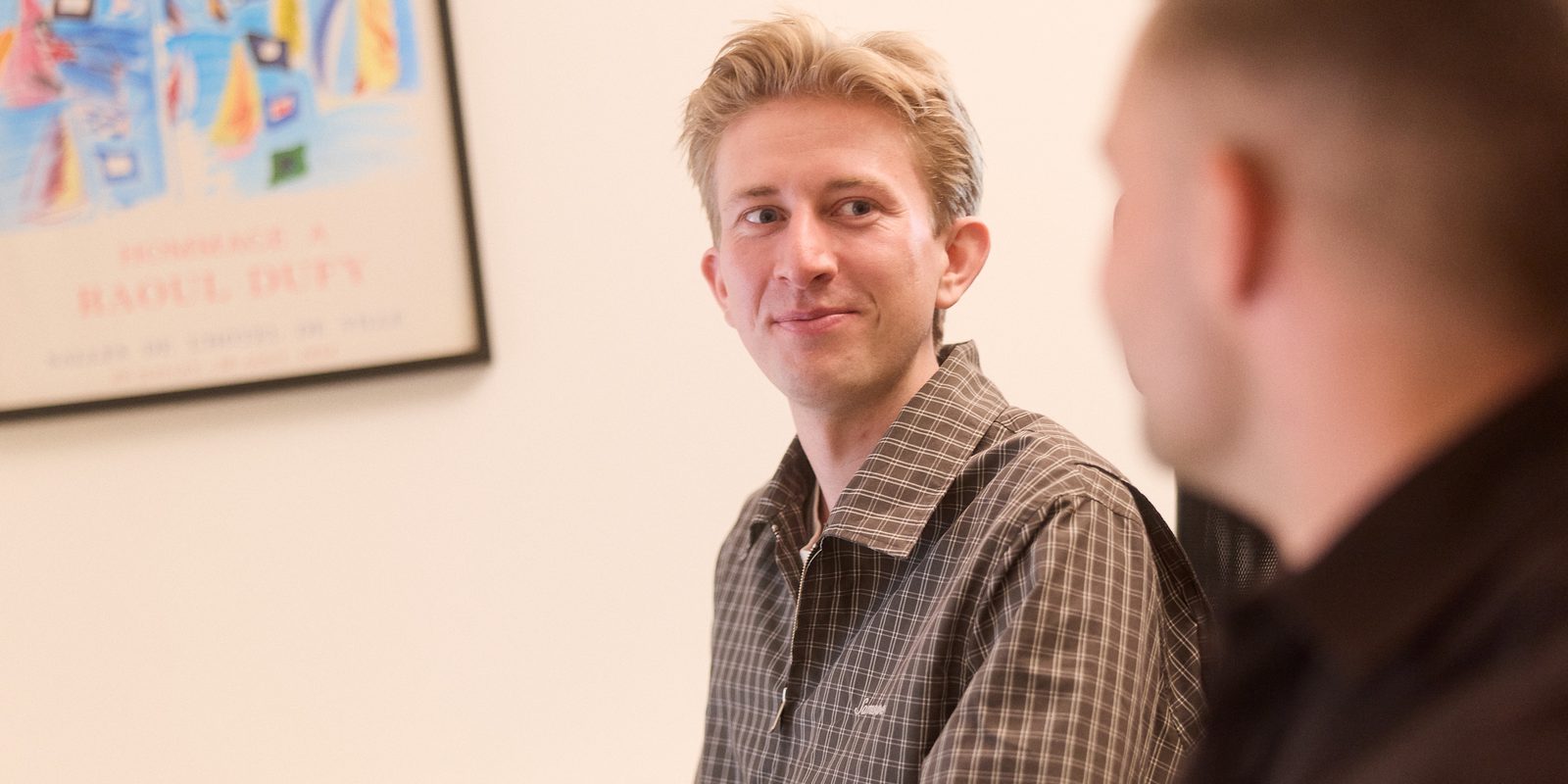 Christian i samtale med en kunde ved et bord, kunden ses bagfra