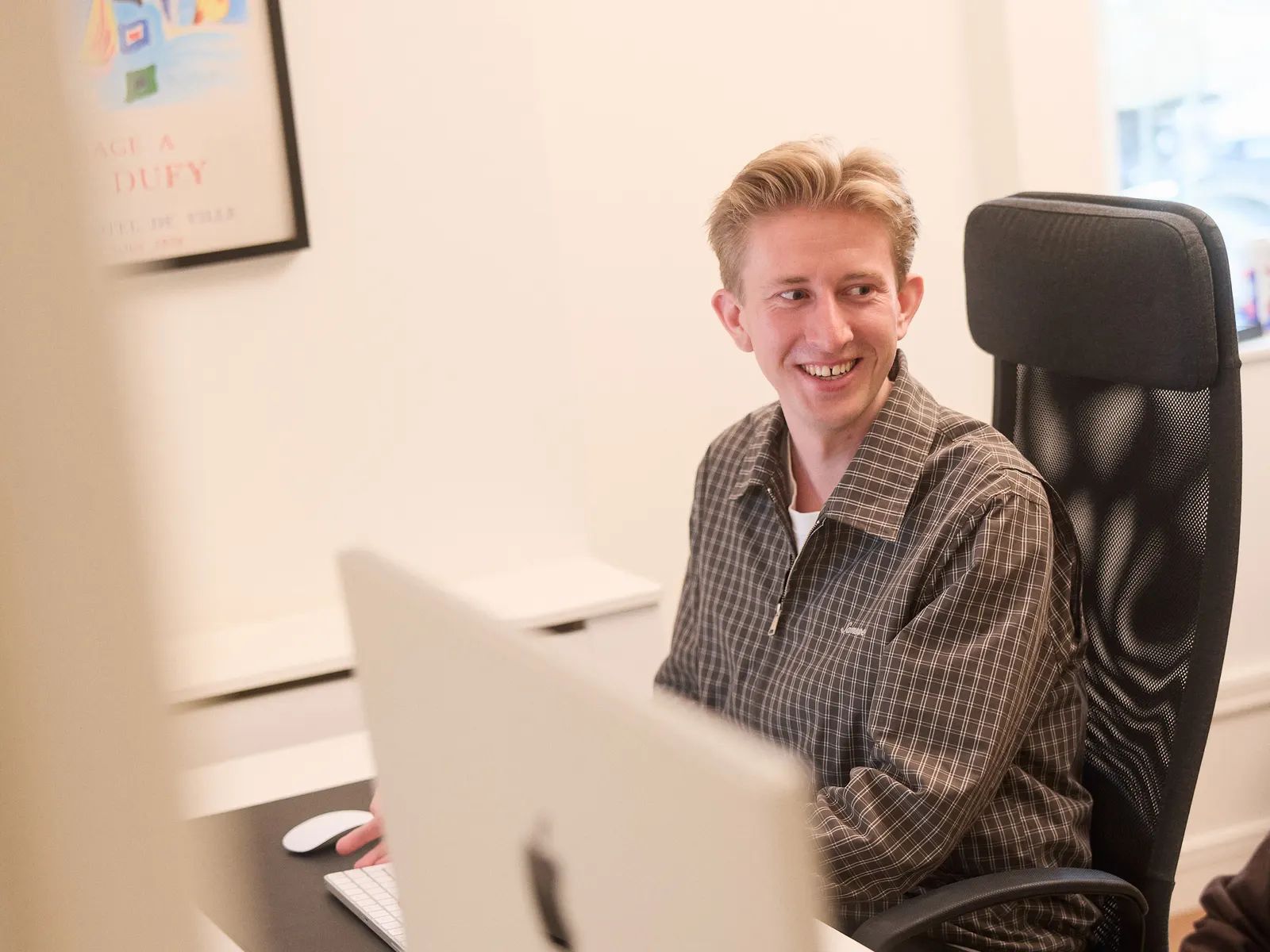 Christian smiling at his desk, screen in front of him.