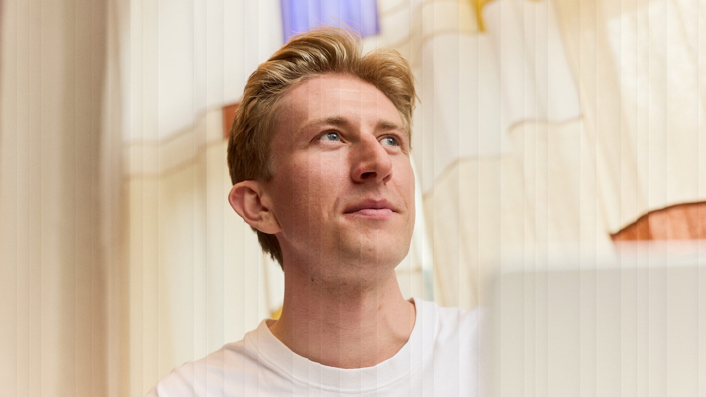 Christian Toft Bach kigger op fra arbejdet, bag riflet glas