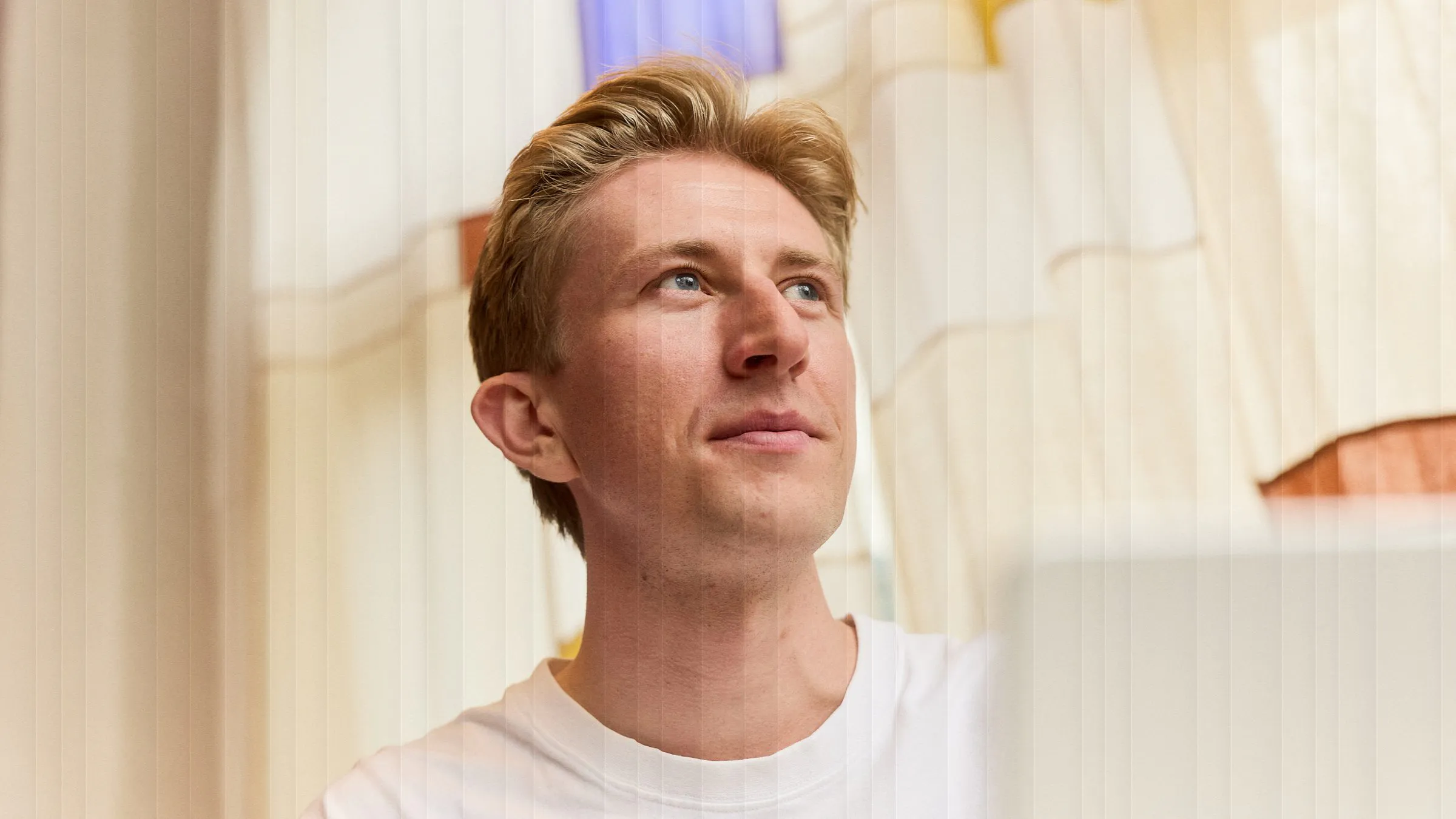Christian Toft Bach kigger op fra arbejdet, bag riflet glas