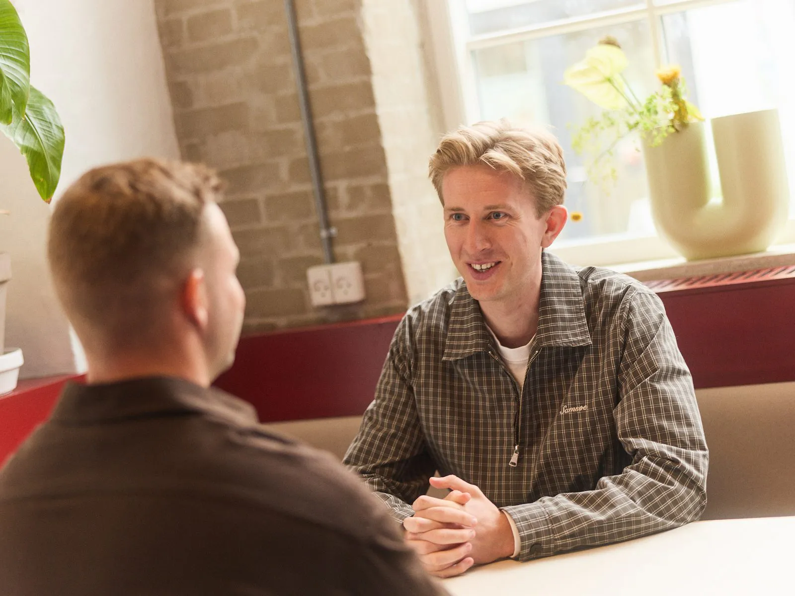 Christian in a working session at a table, in conversation across from a colleague