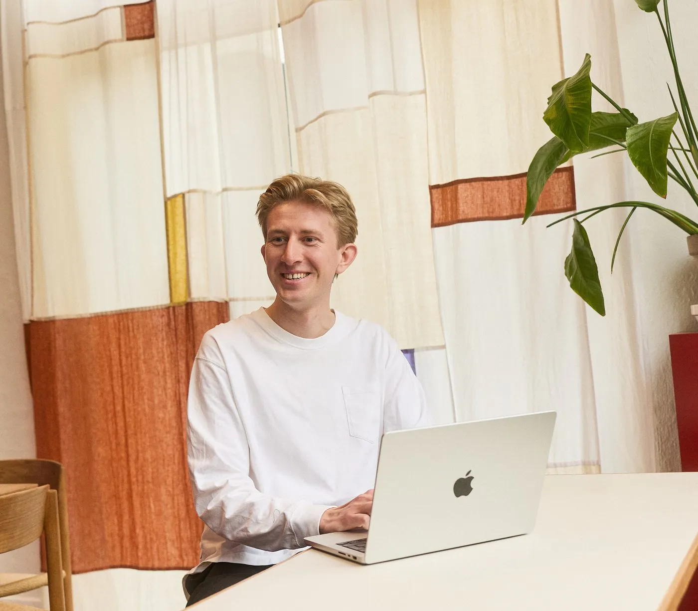 Christian Toft Bach at his desk in front of a woven textile