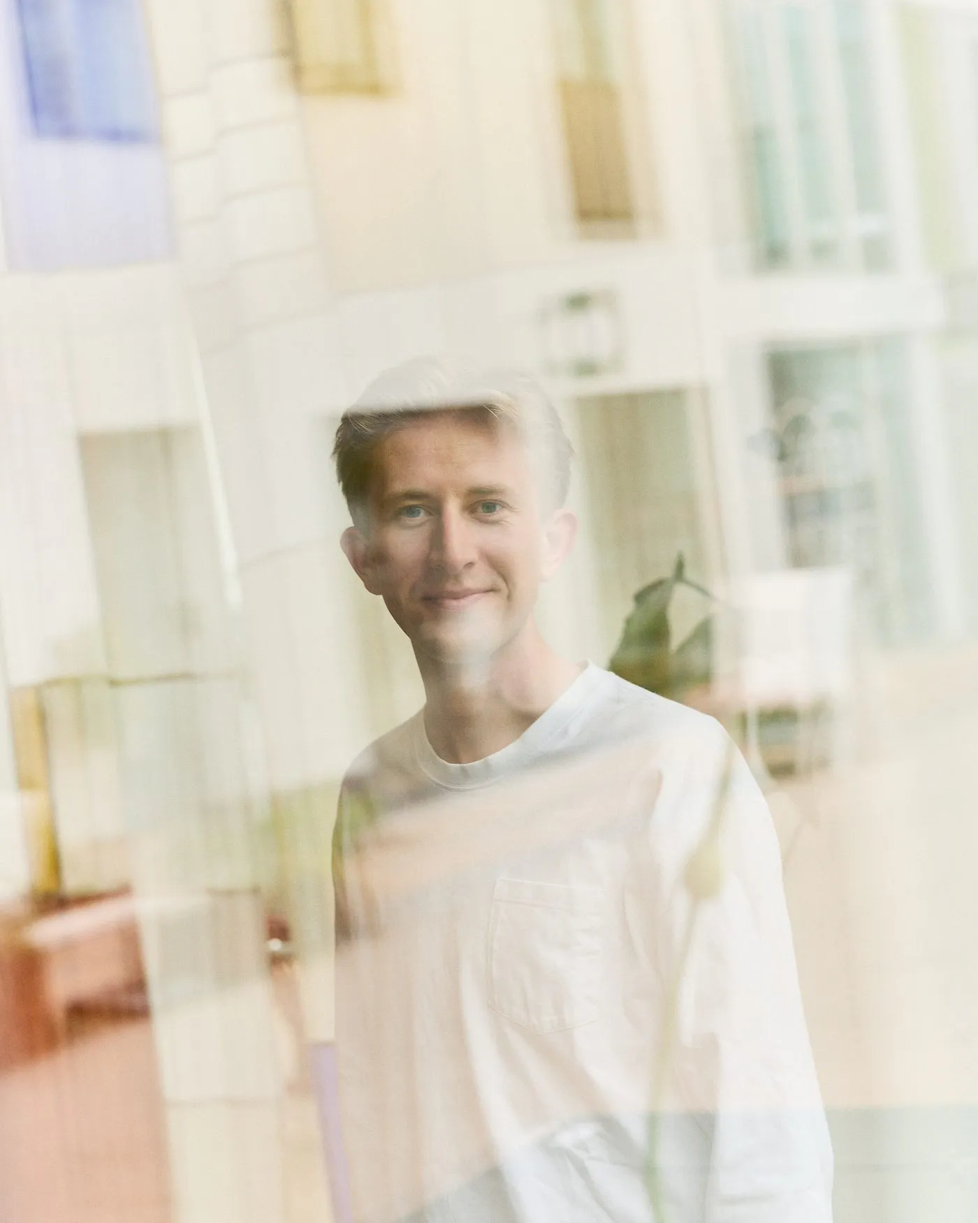 Christian Toft Bach fotograferet gennem en rude, med gadens refleksioner hen over glasset