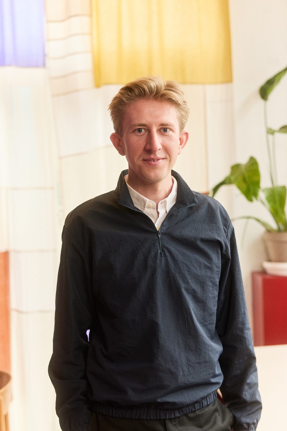 Christian Toft Bach i mørkeblå trøje foran et vævet tekstil